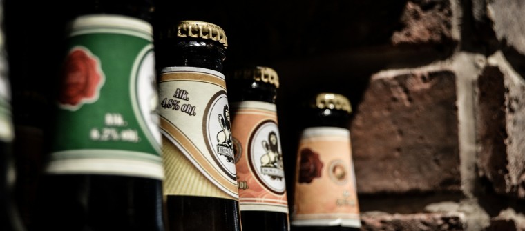 Close up on necks of beer bottles with various labels